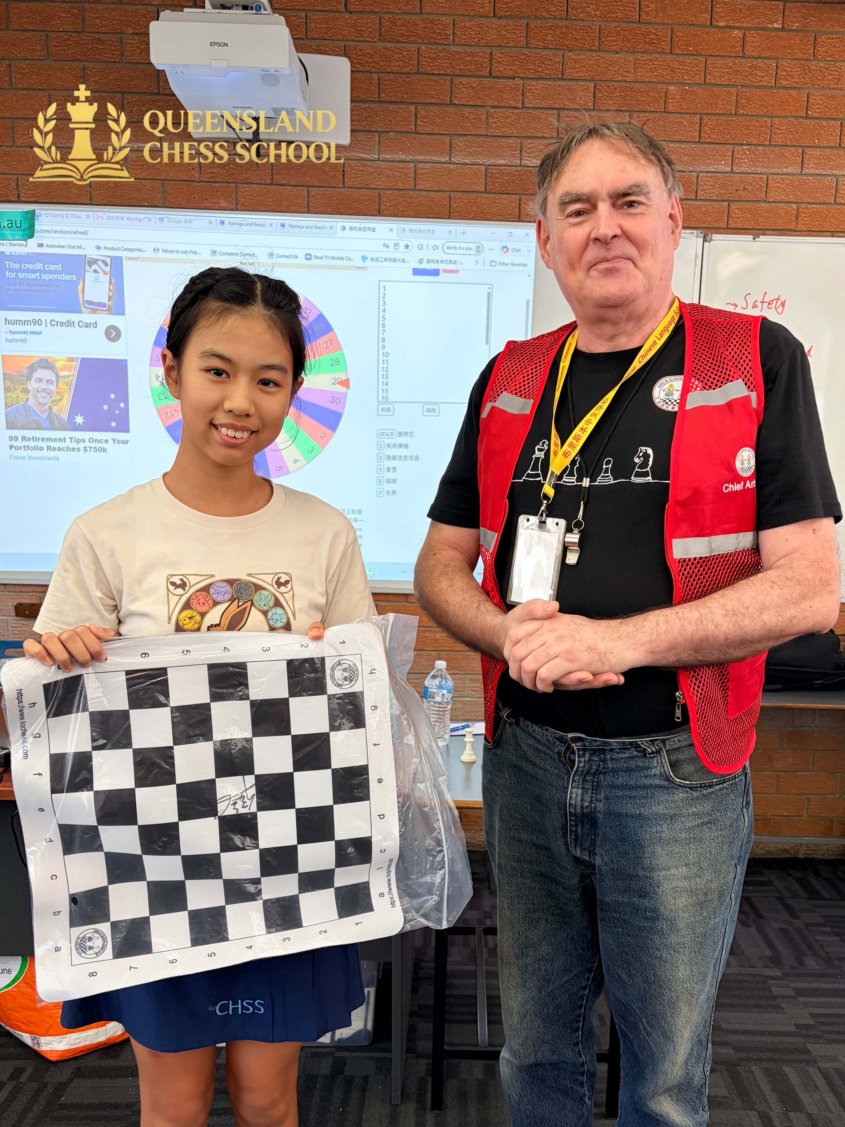 Isabella Lin holding GM Hou Yifan signed chessboard prize